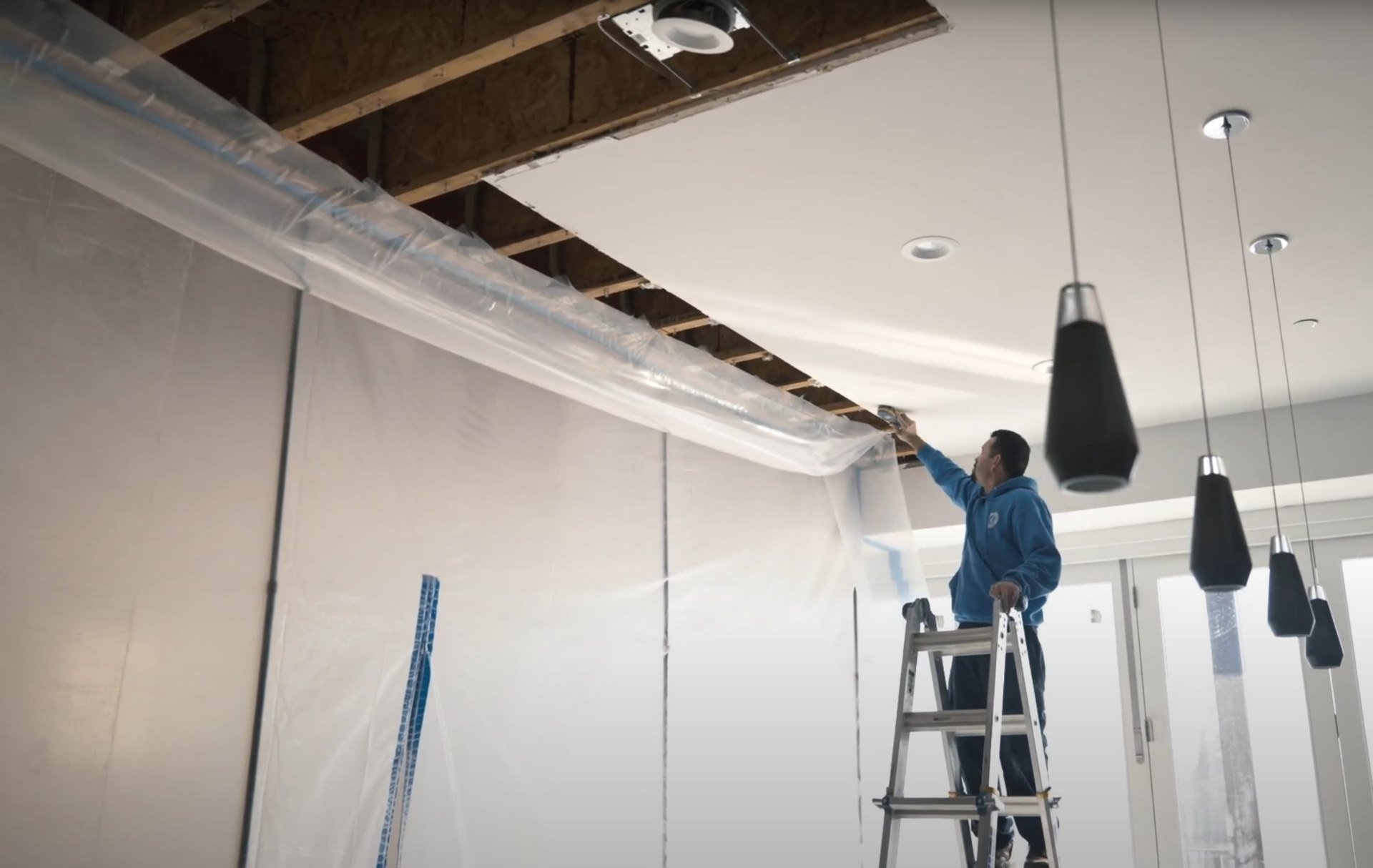 Emergency water damage response and protective covering services in Huntersville Water damage restoration professional covering ceiling and protecting area during emergency water damage response