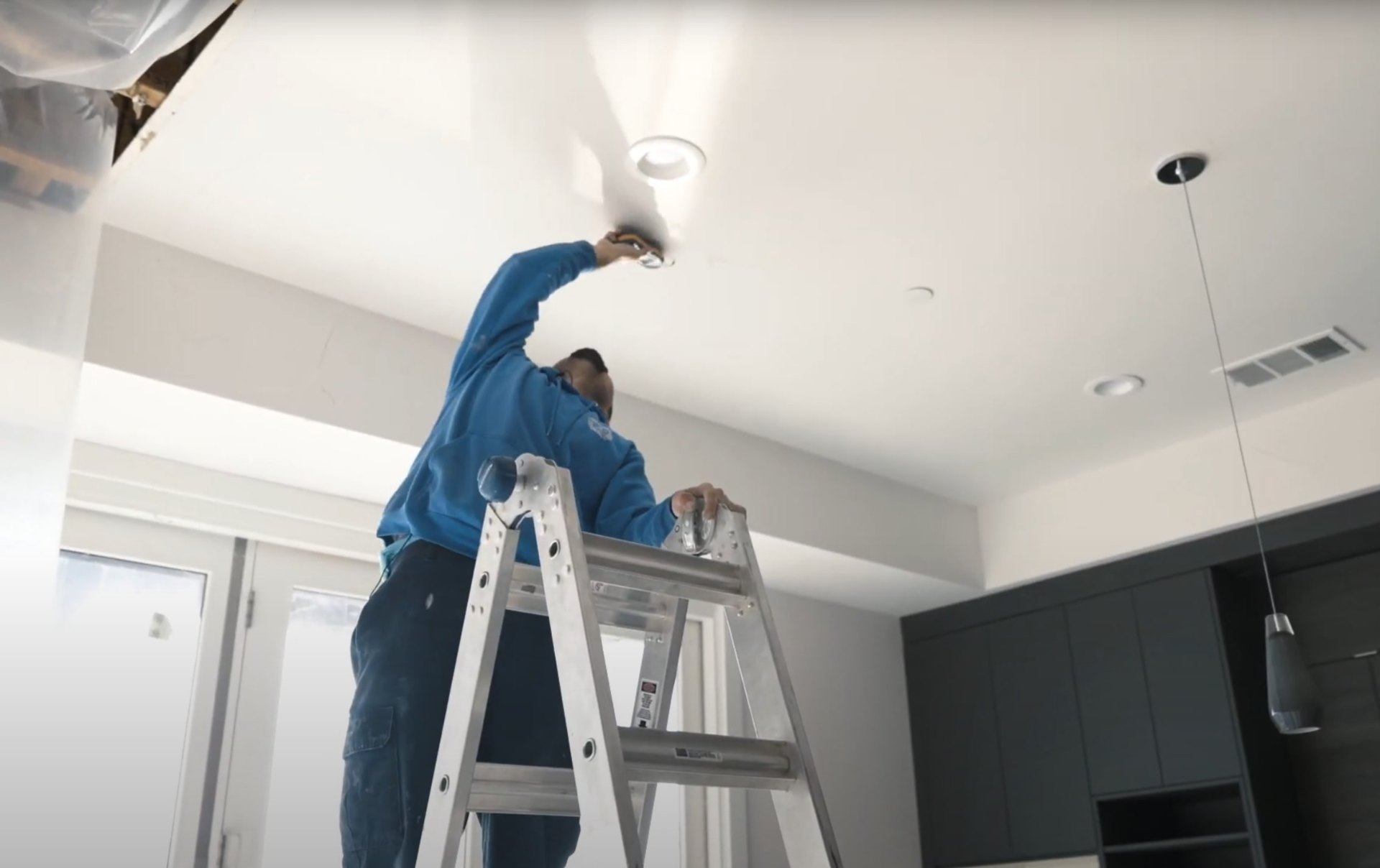 Professional ceiling water damage repair and structural restoration services Water damage restoration technician on ladder performing ceiling repair and moisture remediation